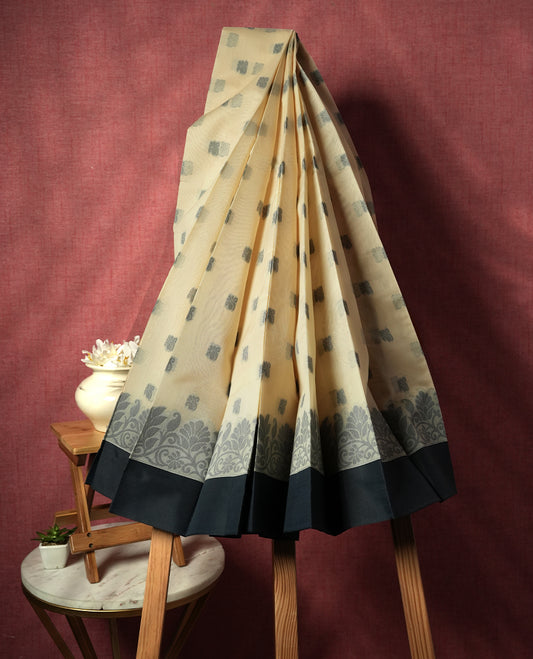 Sandal colour silk cotton saree featuring subtle elegant floral woven motifs on the body, complemented by a classic contrast grey colour border and pallu with intricate traditional detailing & Comes with a matching blouse piece.