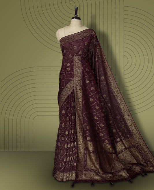 Dark maroon colour semi Banarasi Tussar Georgette saree with gold zari motifs on the body, a grand woven golden pallu, and ornate zari border. Includes a matching blouse piece for a complete look.