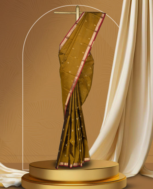 Dusty mustard yellow soft silk saree enhanced with delicate zari buttas, paired with a striking rust orange zari border and elegant pallu & Comes with a matching blouse.
