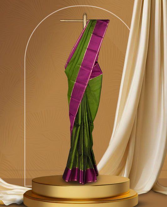 Leaf green colour soft silk saree adorned with intricate self striped, enhanced by a vibrant magenta pink zari border and pallu with rich detailing & paired with a matching blouse.