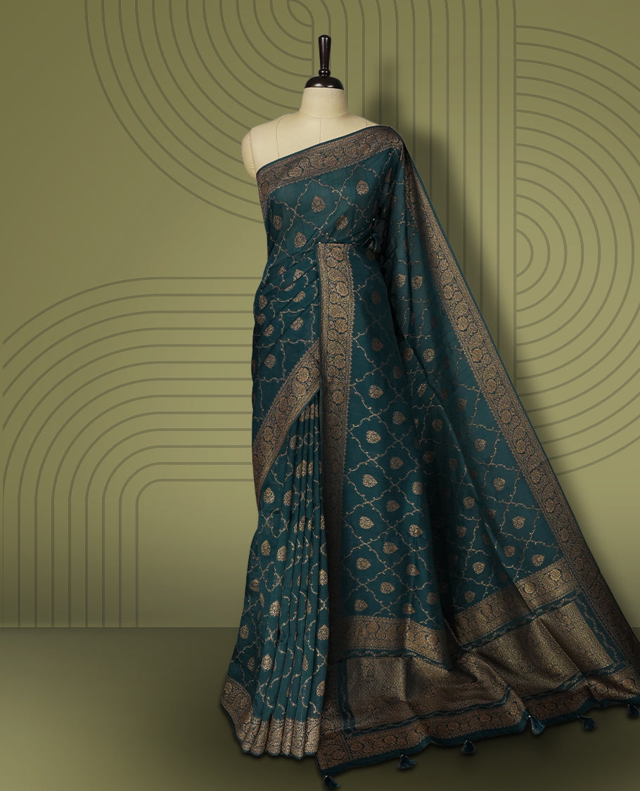 Deep peacock blue colour semi Banarasi Tussar Georgette saree with gold zari motifs on the body, a grand woven golden pallu, and ornate zari border. Includes a matching blouse piece for a complete look.