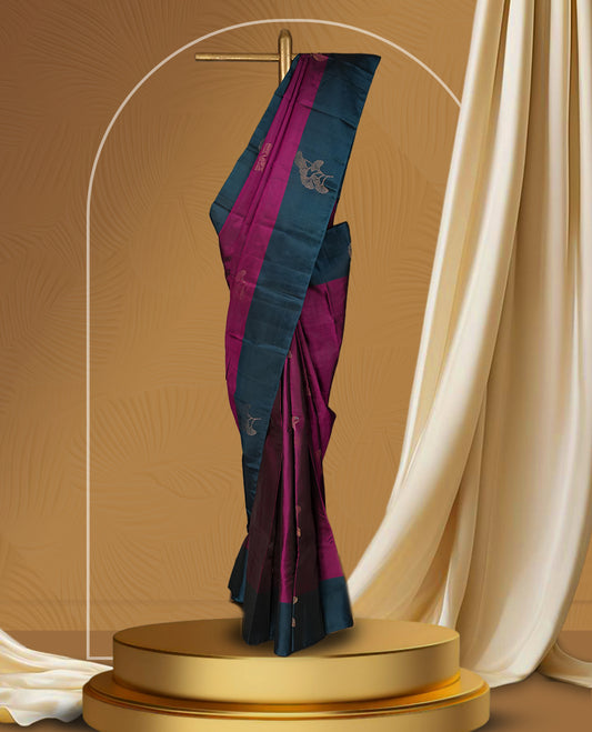 Dark magenta colour soft silk saree adorned with golden zari motifs, enhanced by a deep peacock zari border and pallu with delicate detailing & paired with a matching blouse.