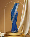 Royal blue colour soft silk saree adorned with small silver buttas, enhanced by a shimmering silver zari border and pallu with delicate motifs & paired with a matching blouse.