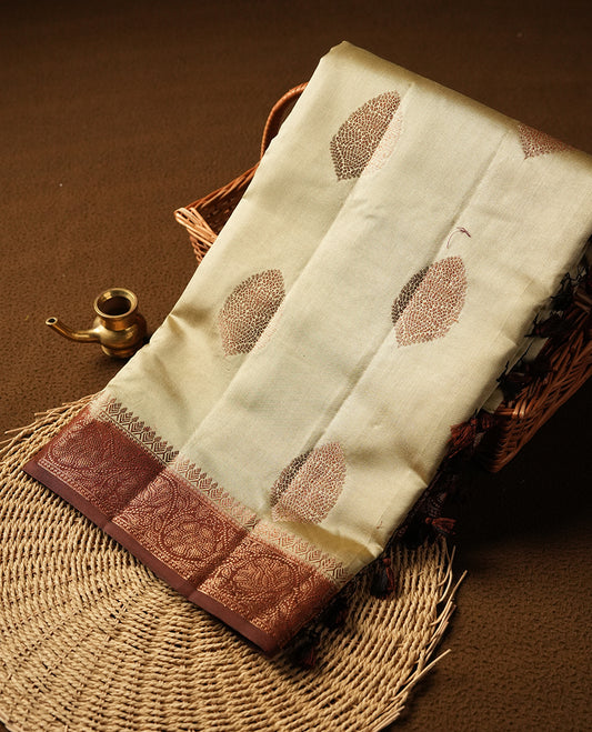 Cream beige Banaras soft silk saree with gold zari oval motifs on body, with contrast Chocolate brown colour floral pattern on pallu, border, and Matching blouse.