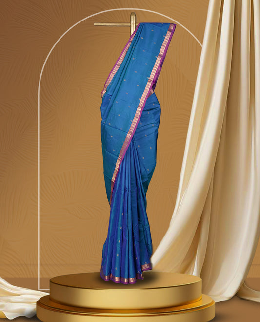 Blue colour soft silk saree adorned with delicate zari buttas, complemented by a rich contrast purple border with intricate golden zari work & Paired with a matching blouse.