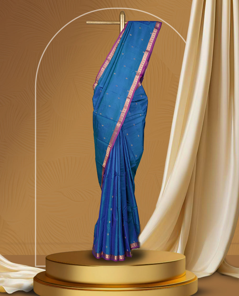 Blue colour soft silk saree adorned with delicate zari buttas, complemented by a rich contrast purple border with intricate golden zari work & Paired with a matching blouse.