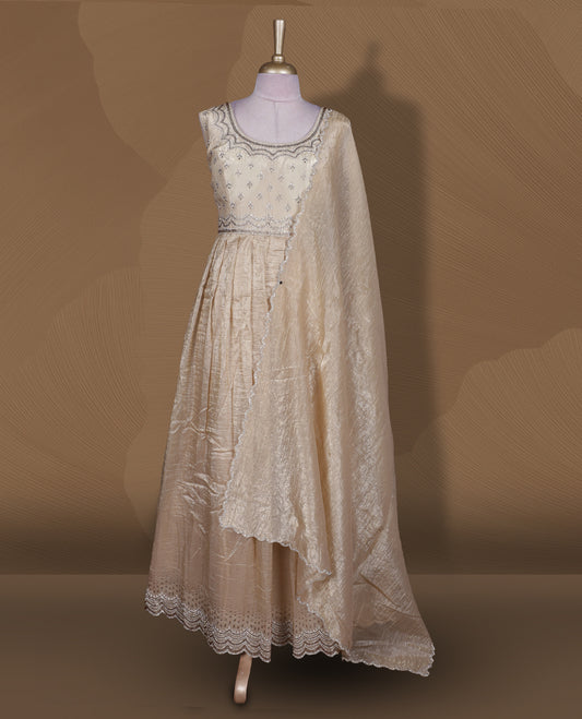 Champagne beige colour stitched gown set with sleeveless embroidered yoke, flared ankle‑length silhouette, and attached dupatta featuring delicate butti work and scalloped beaded edging.