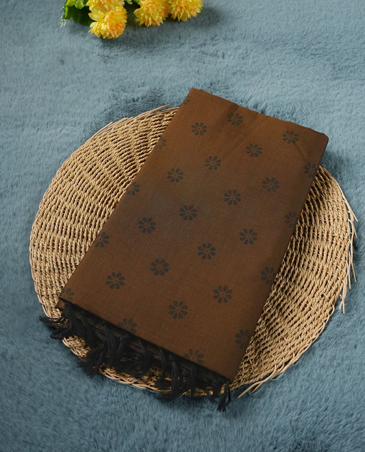 Brown colour poly cotton saree with black floral butti motifs on the body, paired with a matching pallu featuring black ornate floral jaal and stripes on the border, and a coordinated all‑over black paisley printed blouse piece.