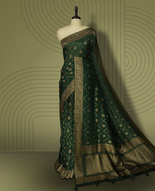 Dark green colour semi Banarasi Tussar Georgette saree with gold zari motifs on the body, a grand woven golden pallu, and ornate zari border. Includes a matching blouse piece for a complete look.