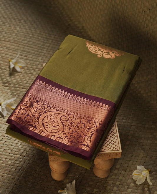 Mehandi colour Semi Silk Saree with copper zari stripes on the body, paired with a contrast dark brown colour pallu with copper zari traditioal border, and a matching blouse piece.