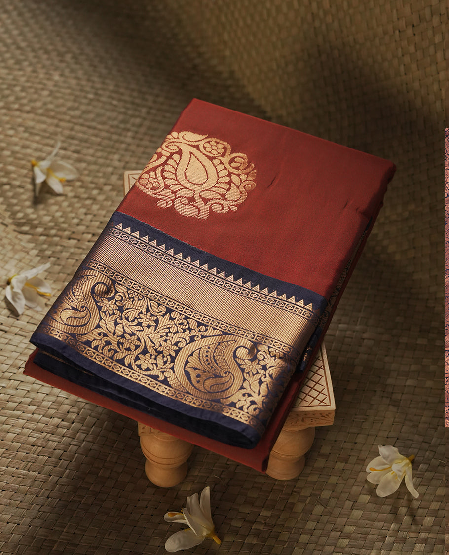 Burgundy colour Semi Silk Saree with gold zari motifs on the body, paired with a contrast Dark blue colour pallu with copper zari traditioal border, and a matching blouse piece.