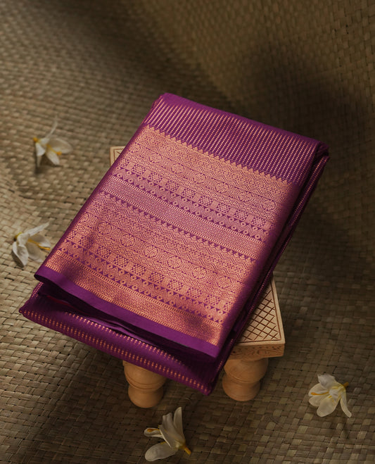 Dark Purple colour Semi Silk Saree with gold zari stripes on the body, paired with a contrast rani pink colour pallu with self colour gold zari traditioal border, and a matching blouse piece.