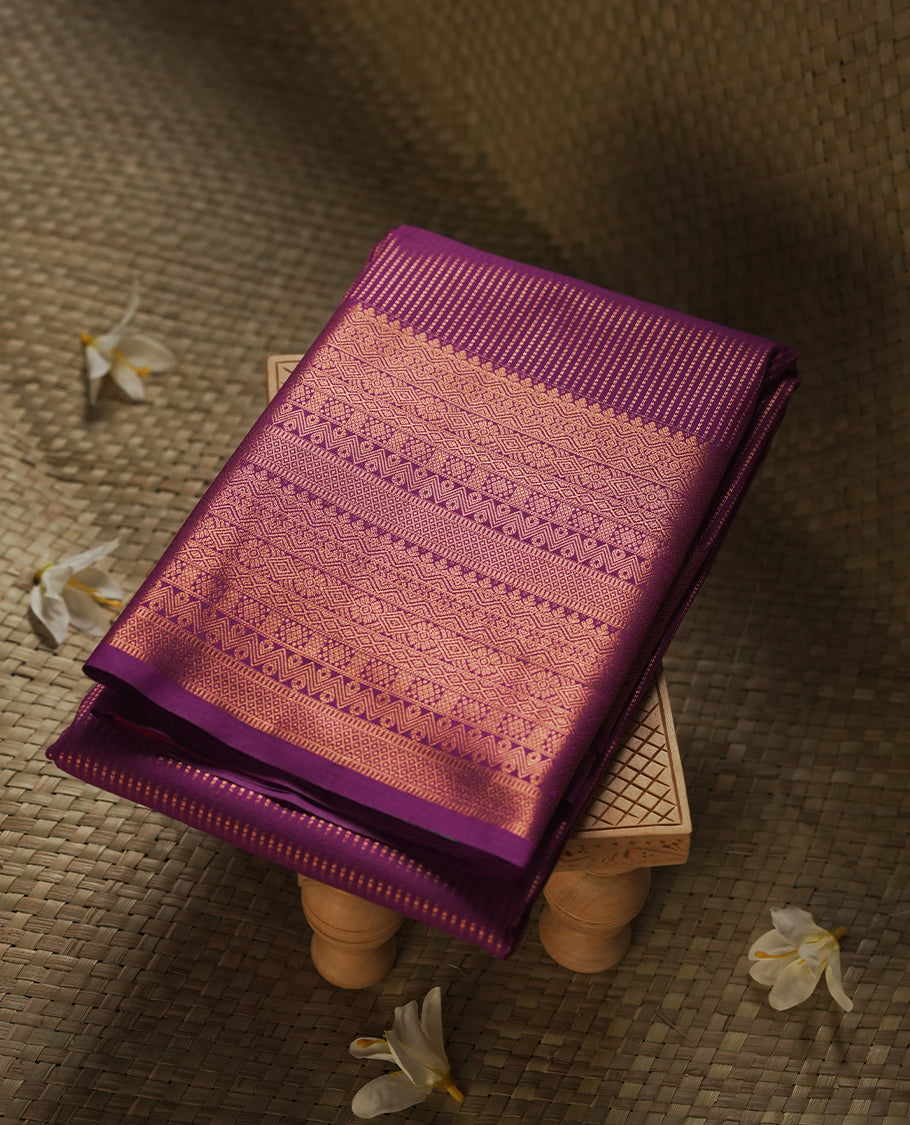 Dark Purple colour Semi Silk Saree with gold zari stripes on the body, paired with a contrast rani pink colour pallu with self colour gold zari traditioal border, and a matching blouse piece.