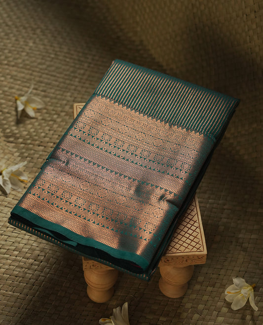 Dark green colour Semi Silk Saree with gold zari stripes on the body, paired with a contrast rani pink colour pallu with coppper zari traditioal border, and a matching blouse piece.