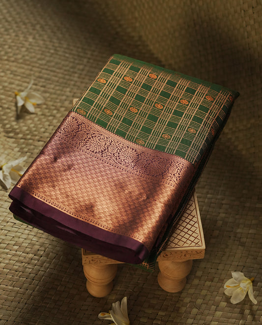 Dark green colour Semi Silk Saree with gold zari stripes on the body, paired with a contrast Burnt maroon colour pallu with gold zari traditioal border, and a matching blouse piece.