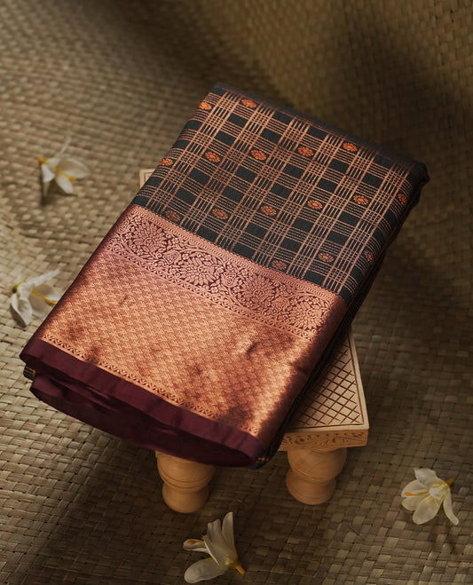 Black colour Semi Silk Saree with copper zari checkered on the body, paired with a contrast chocolate brown colour pallu with coppper zari traditioal border, and a matching blouse piece.