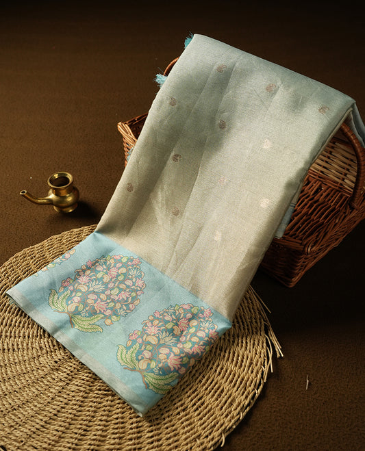 cream beige colour semi tussar saree adorned with gold zari motifs across the body and Floral pattern contrast Light blue colour on border, paired with a matching blouse.