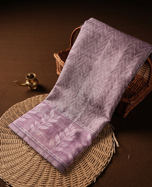 Pink copper colour semi tussar saree adorned with Cream Zigzag printed pattern across the body and Leaf pattern on contrast Dusty pink colour border, paired with a matching blouse.