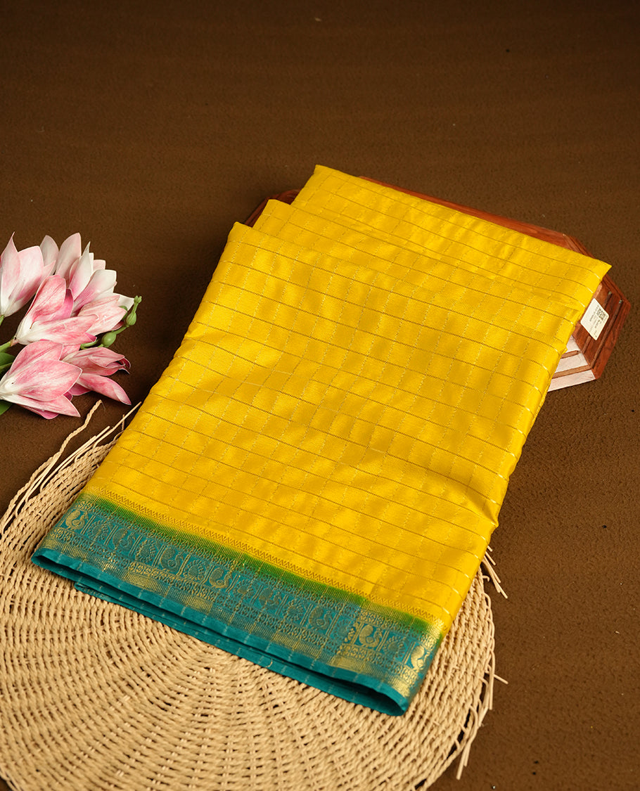 Yellow colour mysore crepe saree with gold zari check pattern on body, complemented by contrast Green colour border featuring peacock and chakkram motifs, paired with matching blouse.