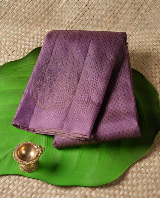Dusty purple colour Vasundhara silk saree featuring self colour zari motifs across the body, finished with a self‑coloured traditional border with kathir motifs and a coordinating blouse.