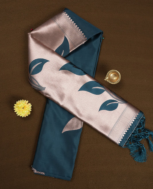 Dark teal blue colour semi silk saree adorned with elegant floral motifs on the body, complemented by a shimmering golden zari-woven pallu and border, and paired with a matching blouse
