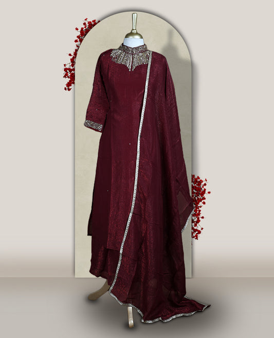 Deep Maroon colour churidar set with a rich sheen, beautifully adorned with golden cut beads work on the neckline and sleeve borders, Paired with a matching dupatta featuring a subtle zari edge, perfect for a regal festive look.