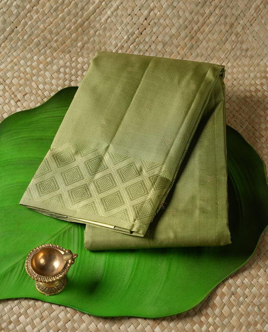 Light mehandi colour Vasundhara silk saree adorned with all-over gold square motifs on the body, complemented by a self colour with green Box pattern border and paired with a matching blouse piece.