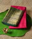Rani pink colour Vasundhara silk saree adorned with all-over gold motifs on the body, complemented by a contrast green with gold tarditional border and paired with a matching blouse piece.