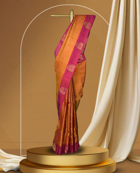 Rich copper brown colour soft silk saree with a contrasting magenta border and pallu, adorned with intricate golden motif & Paired with a matching blouse.