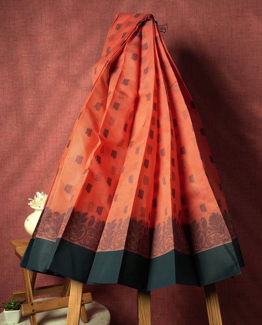 Peach orange silk cotton saree adorned with delicate woven motifs all over the body, paired with an elegant dark grey plain border and richly patterned pallu & Comes with a matching blouse piece for a complete ethnic look.