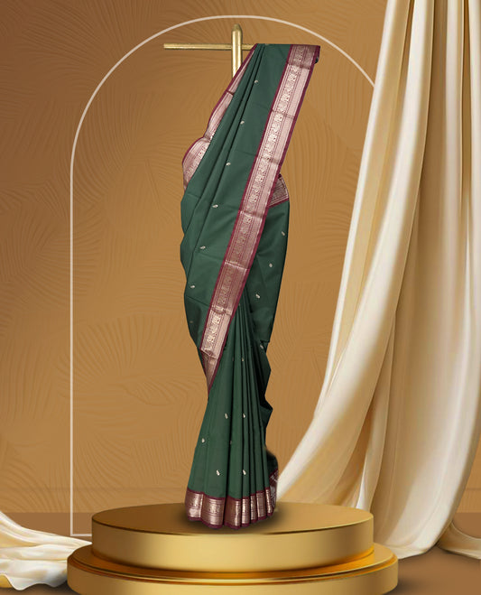 Dark green colour soft silk saree with silver buttas, enhanced by a vibrant maroon zari border and pallu, paired with a matching blouse.