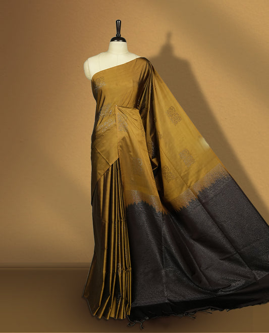 Dark mustard colour semi soft silk saree, adorned with subtle self woven motifs on the body & The design is elevated with an elegant zari border and dark chocolate colour pallu, paired with a matching blouse.