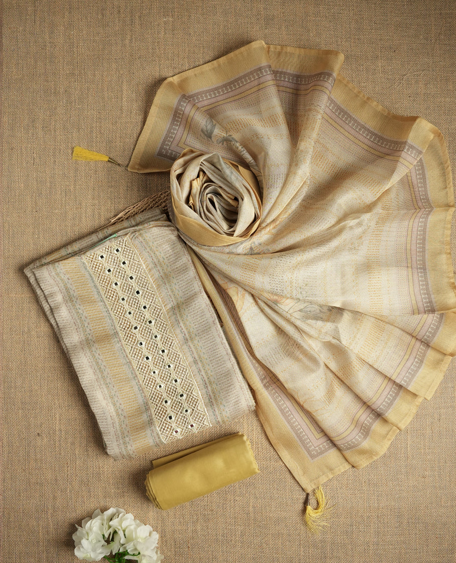 Pastel yellow and beige colour suit material with delicate woven mirror work patterns and subtle zari detailing & Includes a soft dupatta with a floral touch and plain matching bottom.