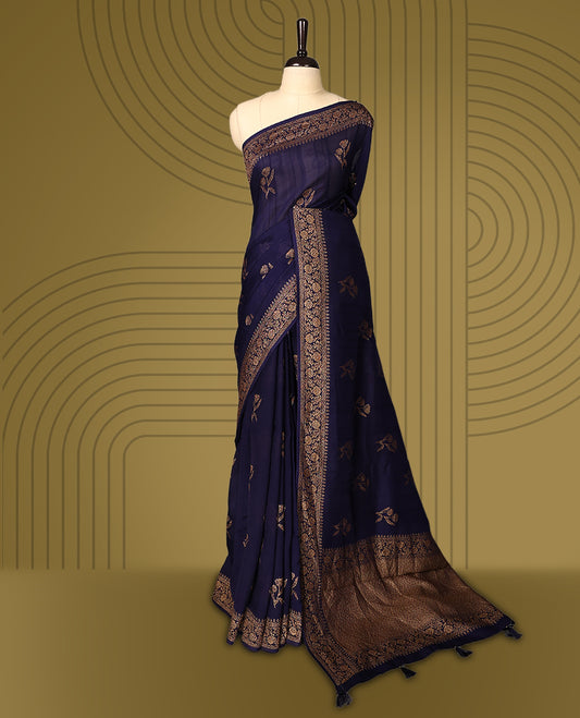 Navy blue semi Banaras tussar saree adorned with golden floral motifs in diagonal patterns across the body and a finely woven zari border, finished with a rich golden pallu, paired with a matching blouse.