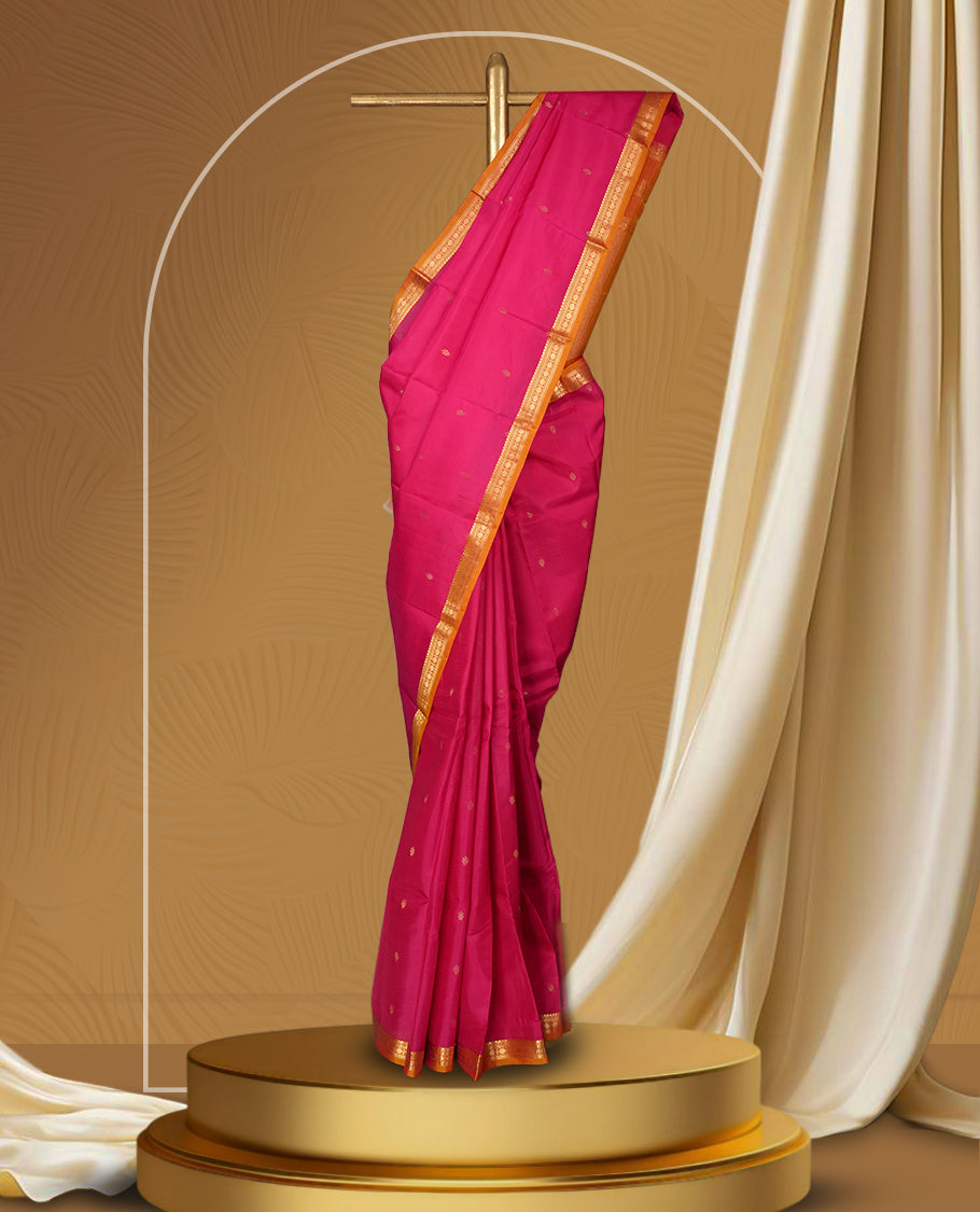Magenta colour soft silk saree with golden buttas, enhanced by a vibrant orange zari border and pallu, paired with a matching blouse.