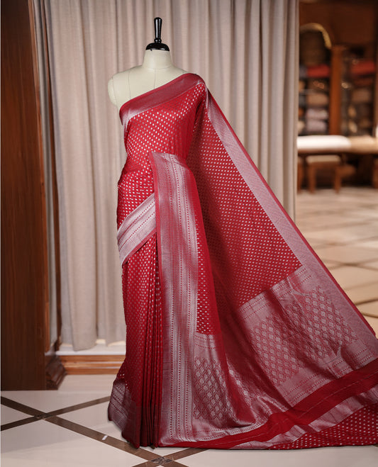 Maroon colour Banarasi silk saree featuring intricate zari weaving and a soft silk texture, Adorned with silver motifs on the body, complemented by a rich Banarasi border and pallu & Comes with a matching blouse.