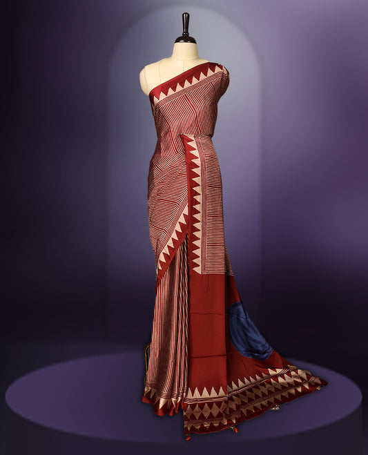 Maroon colour saree featuring bold striped patterns across the body, accentuated with a striking triangular border, and a contrasting pallu with geometric detailing, paired with a matching blouse