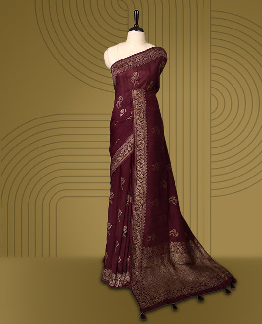Dark coffee brown colour semi Banaras tussar saree adorned with golden floral motifs along the border and scattered designs across the body, finished with a rich golden zari pallu, paired with a matching blouse.