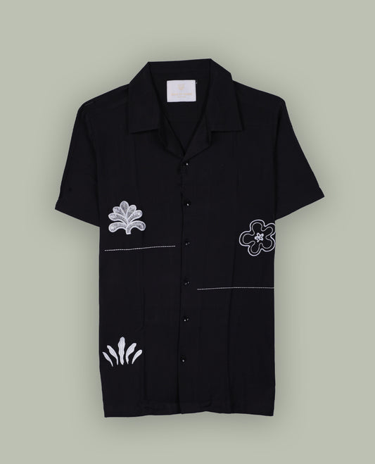Black colour shirt featuring elegant white embroidery motifs on the body, Designed with a classic shirt collar and short sleeves, it blends contemporary style with subtle detailing.