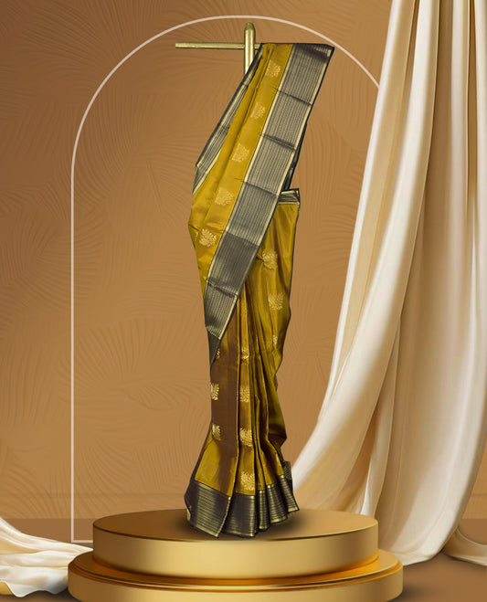 Mustard yellow colour soft silk saree with elegant golden zari motifs, paired with a contrasting dark green border adorned with fine zari stripes & Comes with a matching blouse.