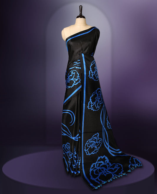 Elegant black colour art silk saree with bold blue floral prints and matching border & Accentuated with a tassel detailed pallu, its perfect for festive evenings or parties. Comes with an unstitched blouse piece.