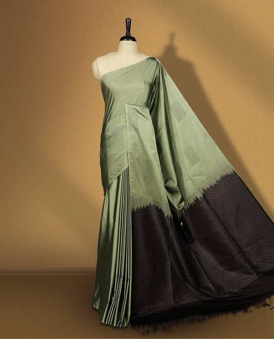 Pastel green colour semi soft silk saree, adorned with subtle self woven motifs on the body & The design is elevated with an elegant zari border and dark chocolate colour pallu, paired with a matching blouse.