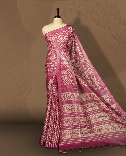 Pink colour semi jute tissue saree featuring delicate wave motifs on the body, complemented by a lustrous zari striped pallu and matching blouse piece for a refined festive look.