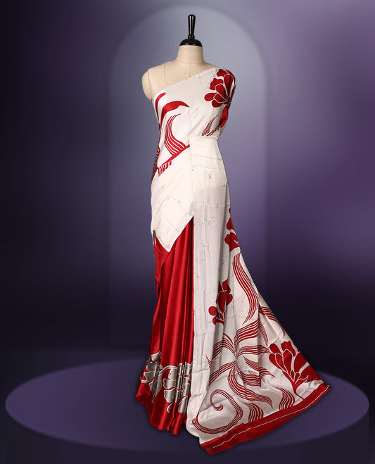 White and red semi modal saree featuring bold floral and abstract patterns across the body and pallu, enhanced with a smooth drape and a matching blouse.
