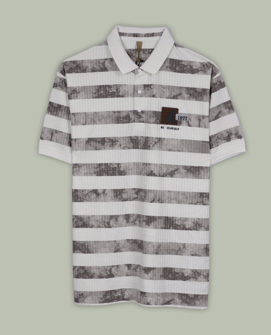 Off white and grey colour striped polo T shirt featuring a collared neck with button placket, half sleeves, and a textured fabric design, enhanced with a front chest patch that adds a trendy casual vibe.