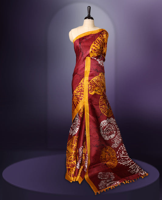 Maroon colour saree adorned with bold yellow and white abstract floral prints across the body and pallu, enhanced by a contrasting mustard yellow border, paired with a matching blouse.