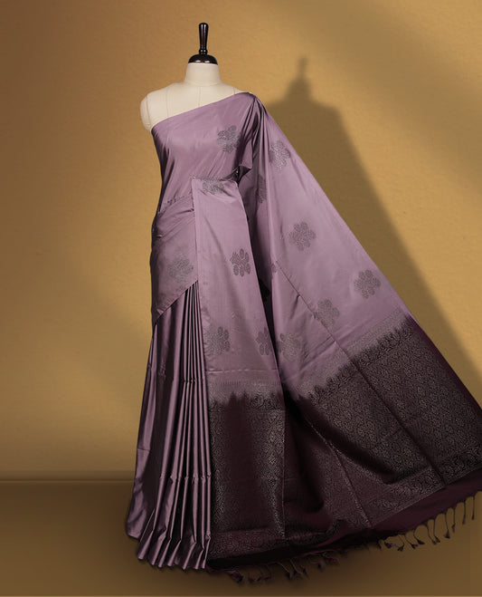 Greyish lavender colour semi soft silk saree, beautifully designed with rich floral woven motifs & The look is enhanced by a rich contrast deep wine border and pallu with tassels, paired with a matching blouse.