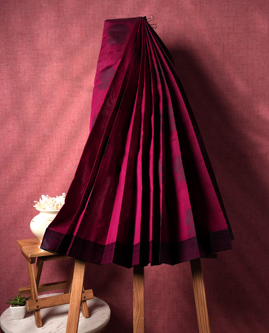 Wine berry colour silk cotton saree featuring elegant floral zari motifs on the body, complemented by a rich contrast dark border and pallu with traditional woven detailing & Comes with a matching blouse piece.