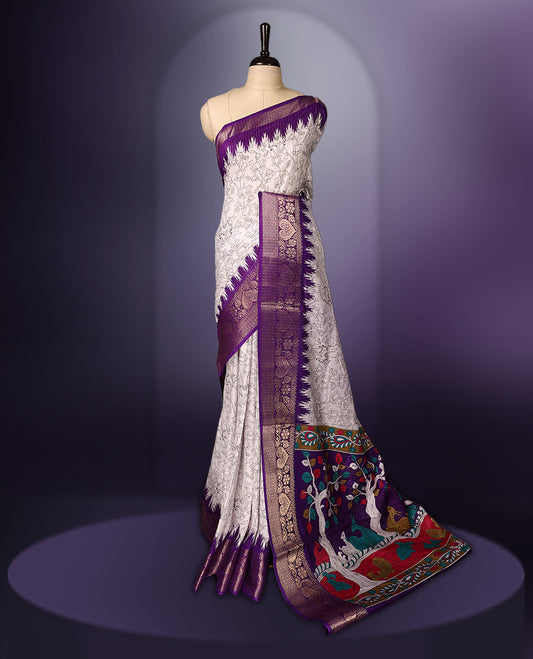 White saree featuring intricate line art motifs all over, elevated with a rich purple and gold zari border & The pallu showcases vibrant multicolor animal and tree designs, paired with a matching blouse.