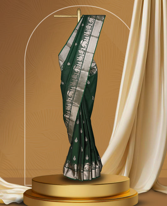 Dark green colour soft silk saree adorned with copper shade buttas, accentuated by a contrasting copper zari border and pallu with intricate motifs & Paired with a matching blouse.